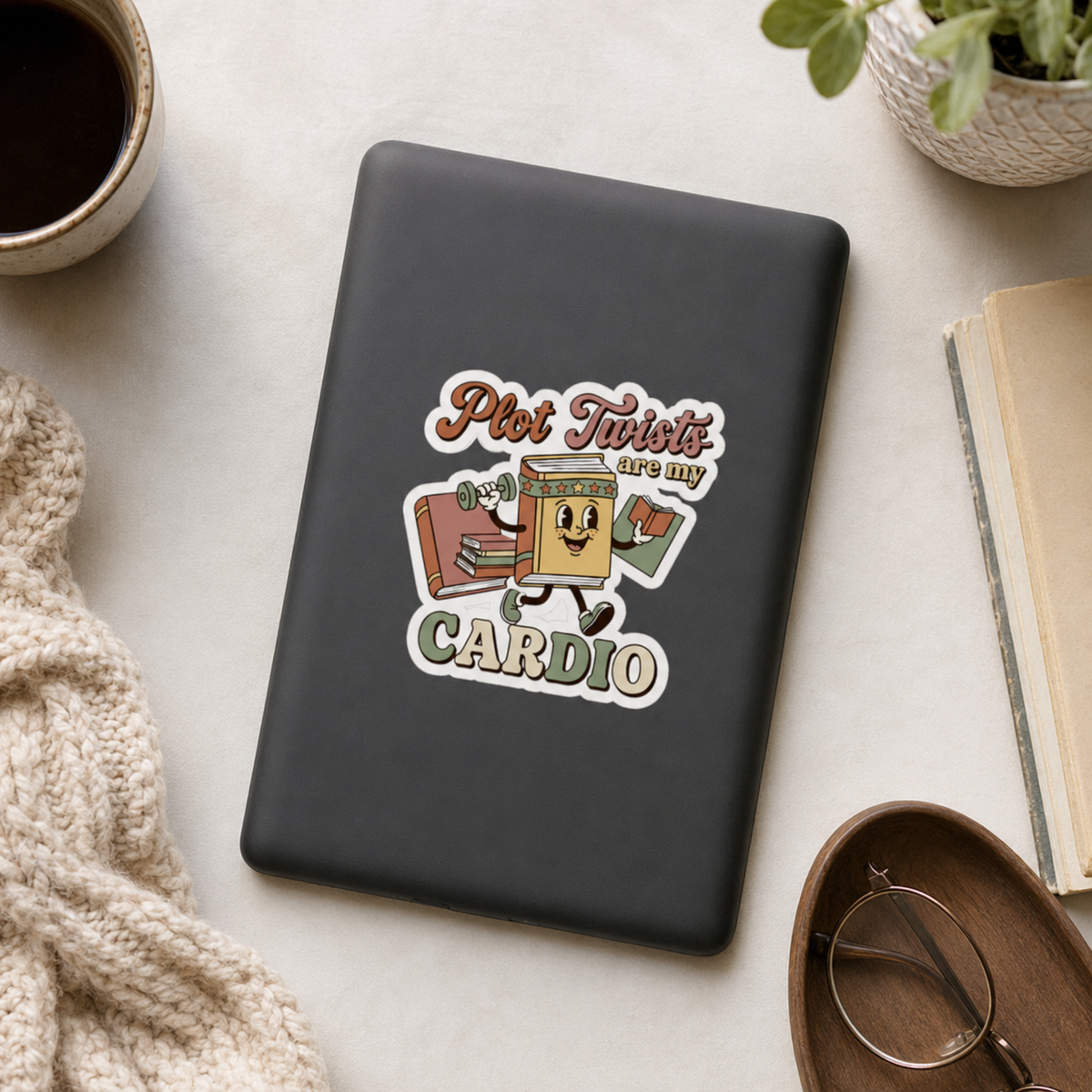 “Plot Twists Are My Cardio” sticker with a smiling cartoon book jogging with a dumbbell and another book, surrounded by coral and sage lettering, shown on a black e-reader.