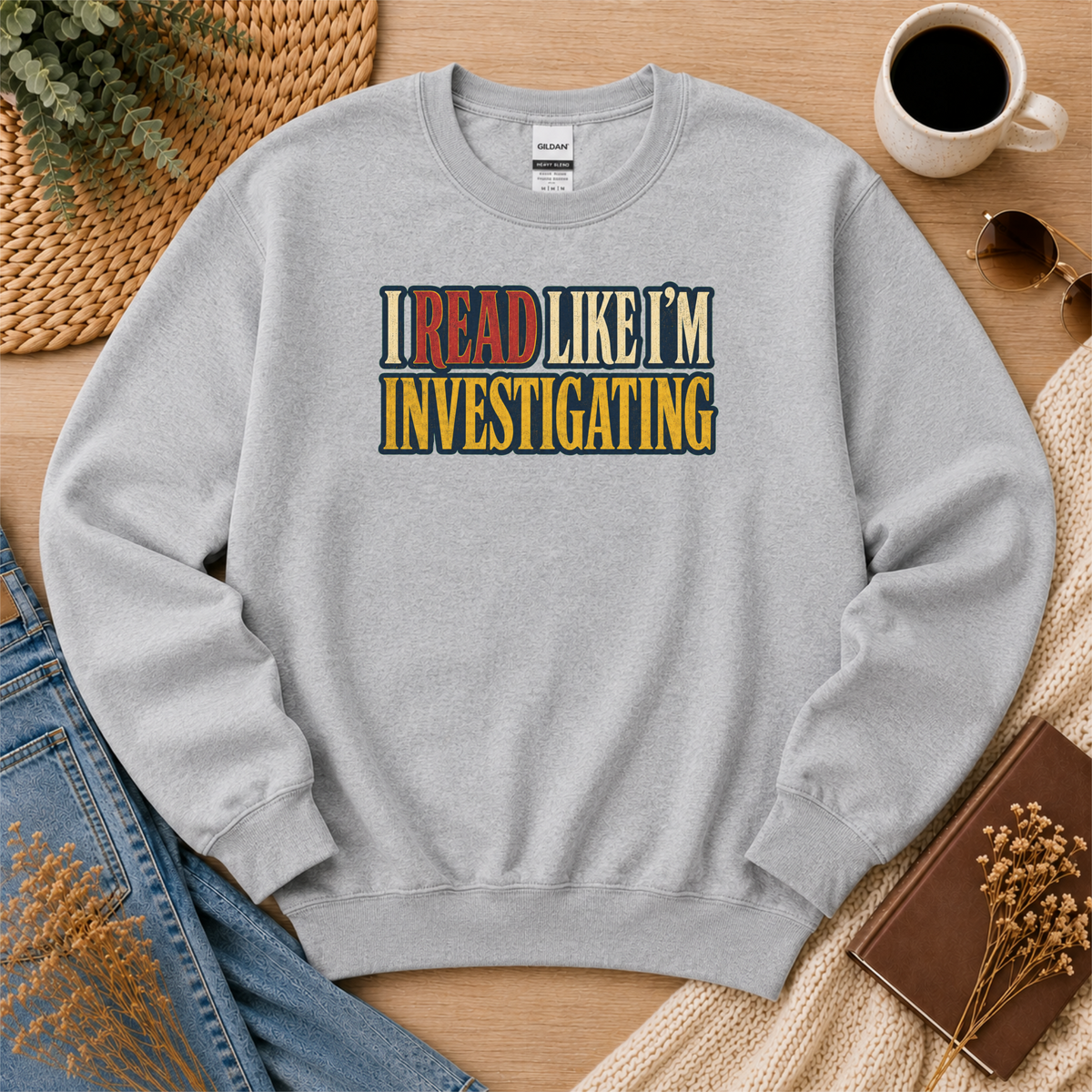 Sport gray crewneck sweatshirt laid flat with bold vintage lettering and the words “I Read Like I’m Investigating.”
