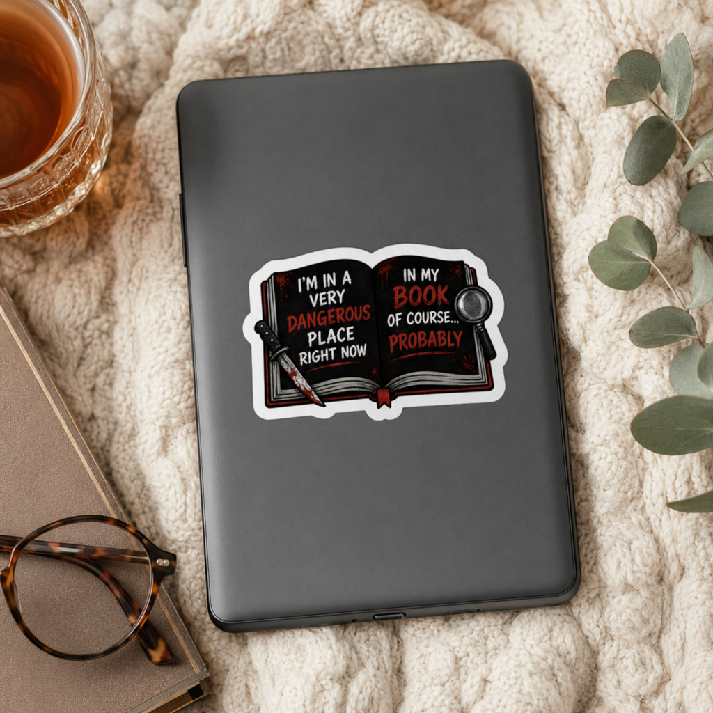 “I’m in a very dangerous place right now. In my book, of course… probably” sticker with an open black book with red and white lettering, a bloodstained knife, and a magnifying glass, shown on a black e-reader.