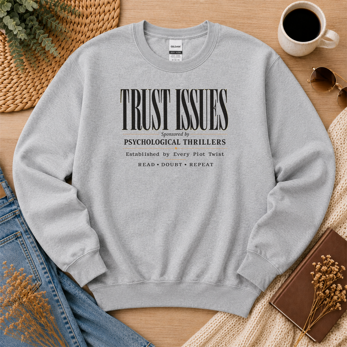 Sport gray crewneck sweatshirt laid flat with stacked typography and the words “Trust Issues. Sponsored by Psychological Thrillers. Established by Every Plot Twist. Read Doubt Repeat.”