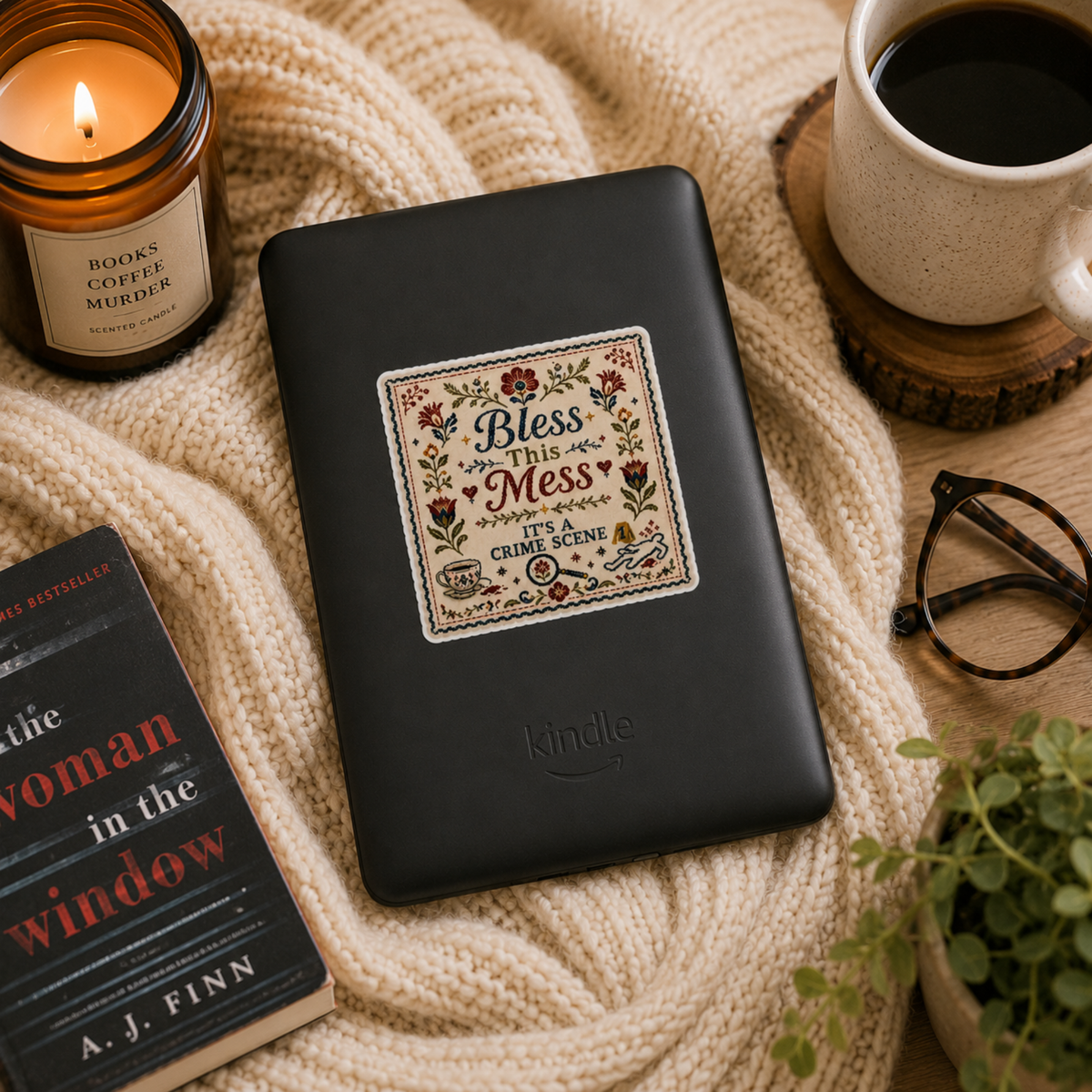 “Bless This Mess. It’s a Crime Scene” sticker with a folk-art floral border, teacup, magnifying glass, evidence marker, and body outline, shown on a black Kindle.