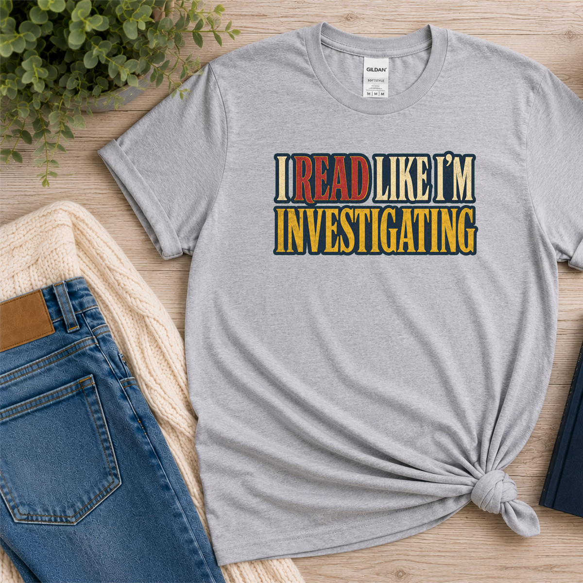 Sport gray T-shirt laid flat with bold vintage lettering and the words “I Read Like I’m Investigating.”