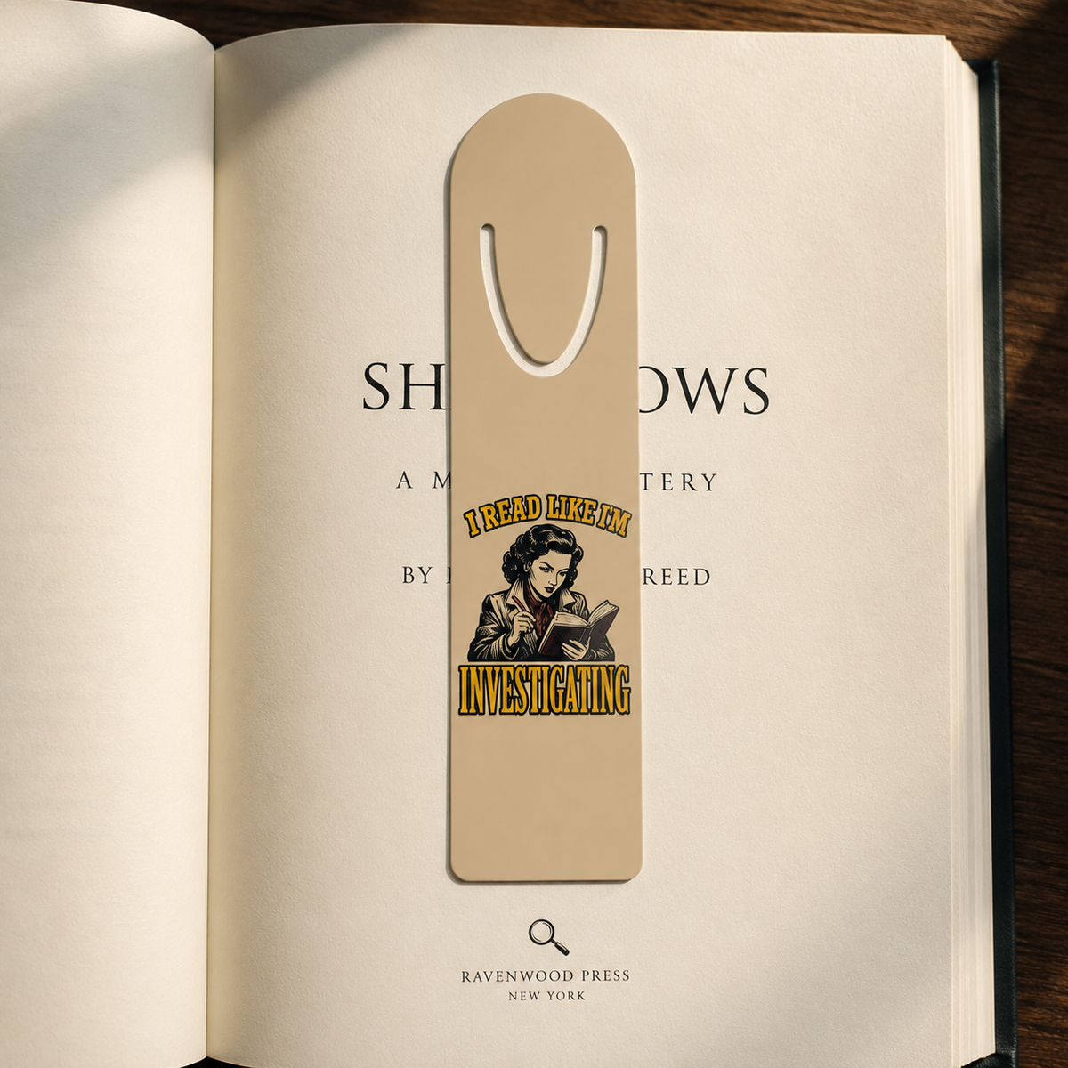I Read Like I’m Investigating aluminum bookmark clipped over the title page of an open mystery novel.
