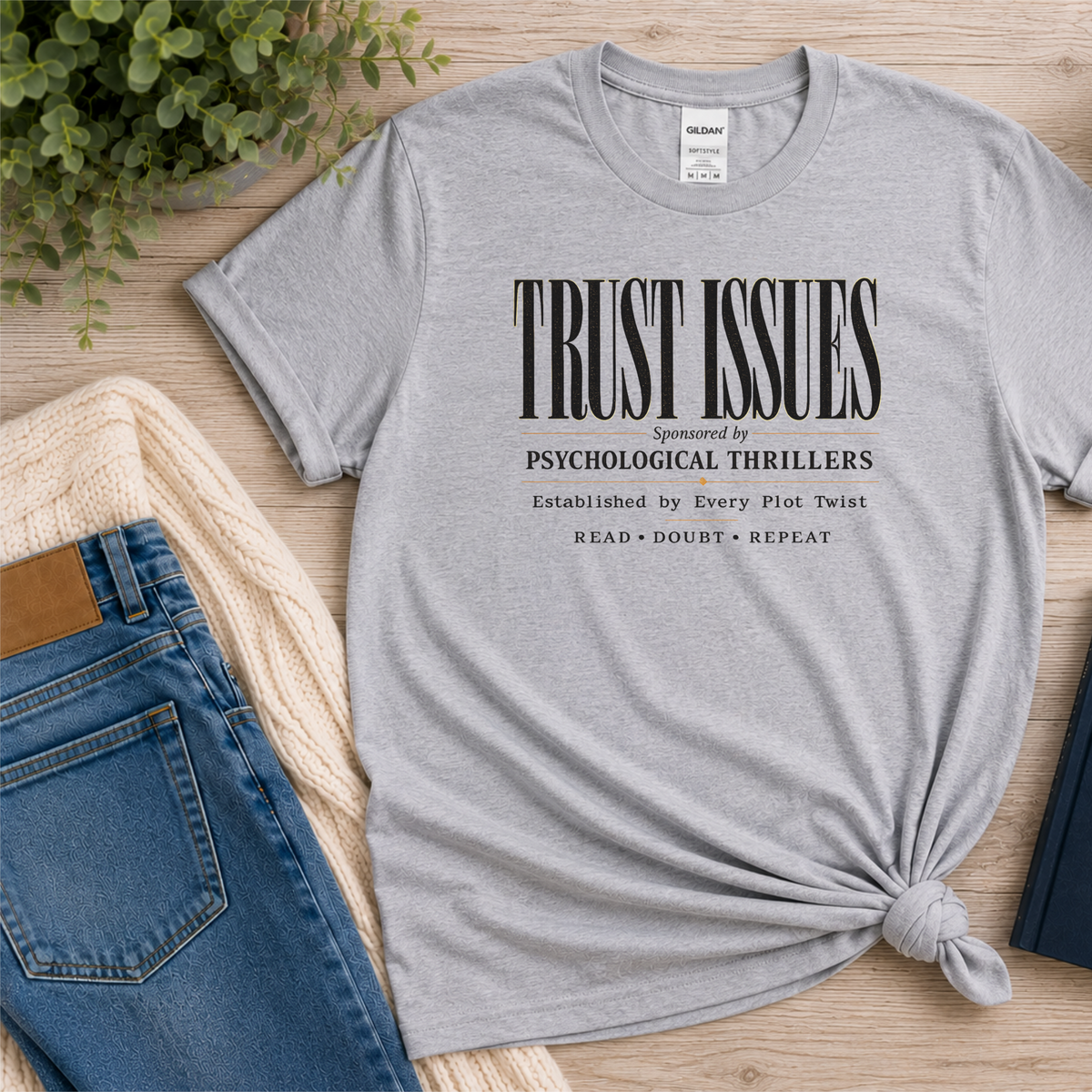 Sport gray T-shirt laid flat with stacked typography and the words “Trust Issues. Sponsored by Psychological Thrillers. Established by Every Plot Twist. Read Doubt Repeat.”