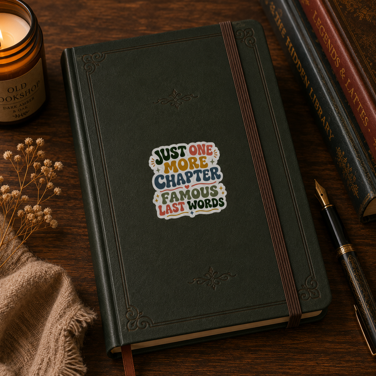 “Just One More Chapter. Famous Last Words” sticker with green, coral, gold, and blue retro lettering with hearts and sparkles, shown on a dark green journal.
