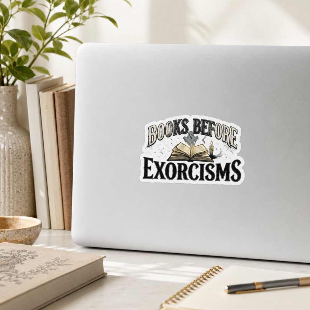 “Books Before Exorcisms” sticker with black lettering, an open book, gray ghost, candle, and cobweb, shown on a silver laptop.