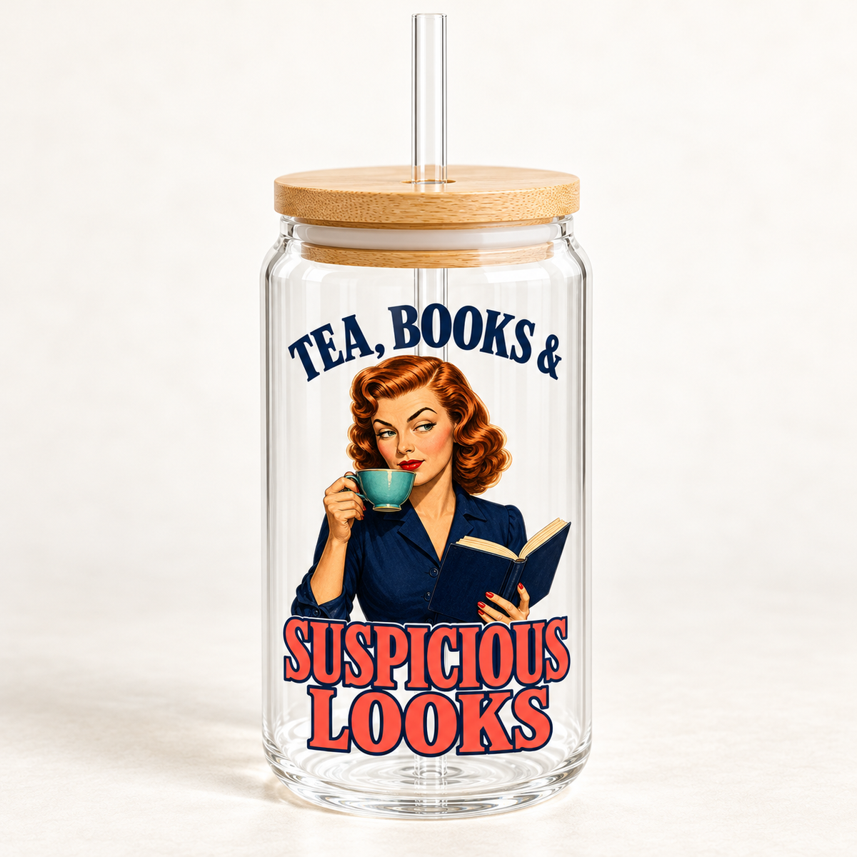 Front view of an empty glass sipper with bamboo lid and clear straw; a red-haired woman holds a teal teacup and navy book beneath “Tea, Books & Suspicious Looks” lettering.