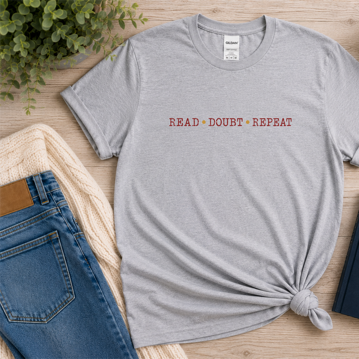 Sport gray T-shirt laid flat with small red lettering across the chest and the words “Read Doubt Repeat.”