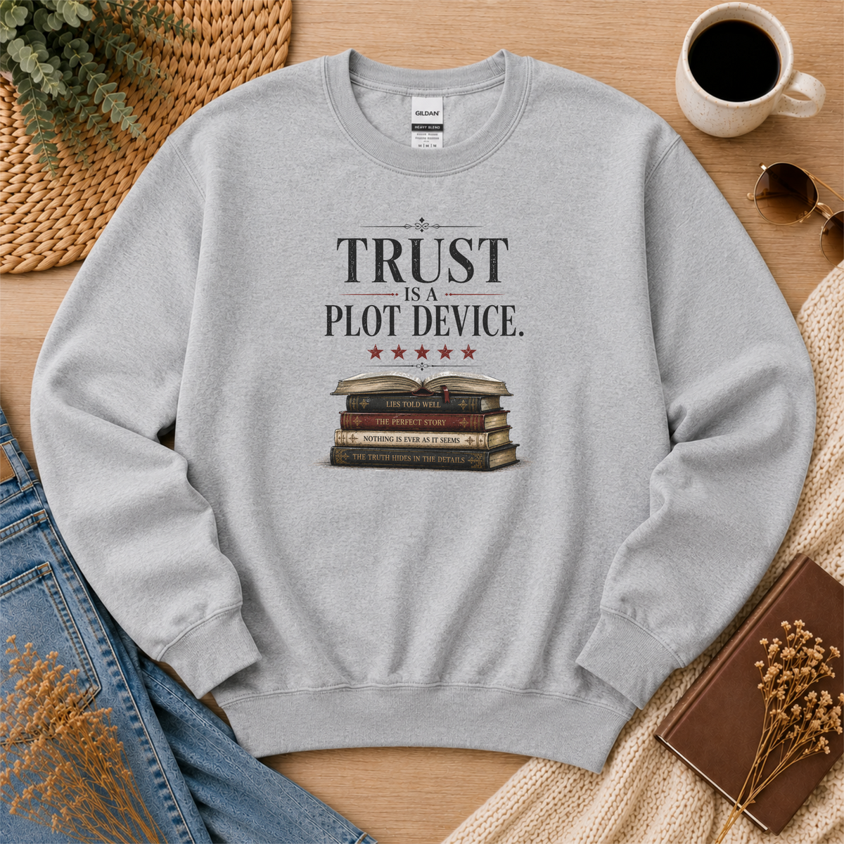 Sport gray crewneck sweatshirt laid flat with stars above a stack of books and the words “Trust Is a Plot Device.”