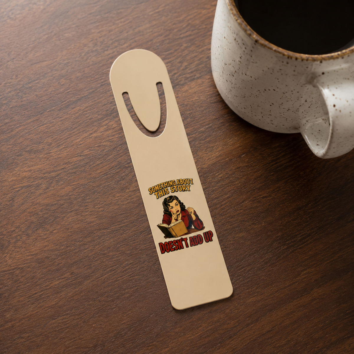 Something About This Story Doesn’t Add Up aluminum bookmark on a dark wood table beside a ceramic mug of coffee.