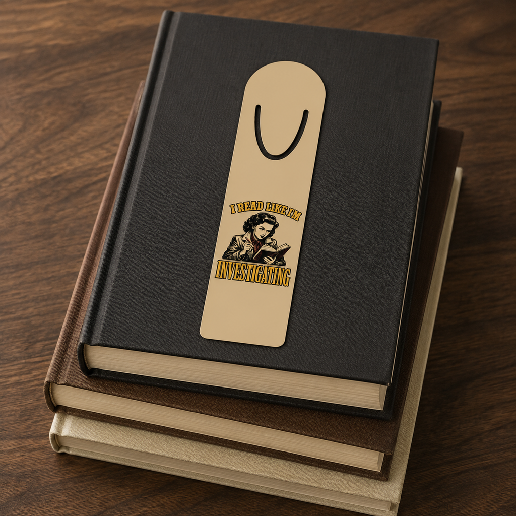 I Read Like I’m Investigating aluminum bookmark displayed on a stack of three closed hardcover books.