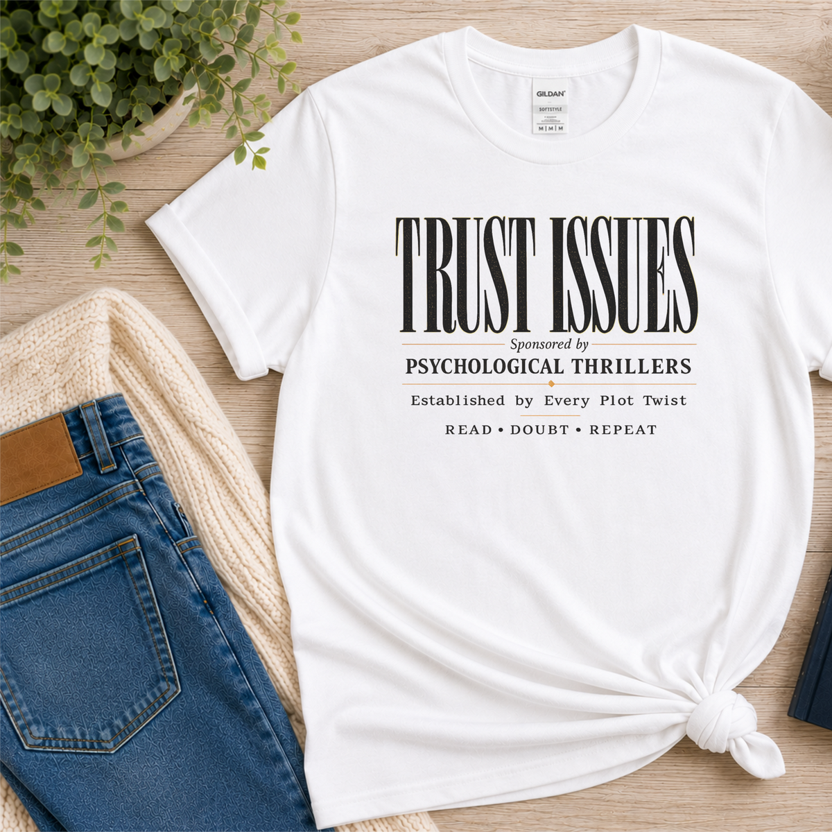 White T-shirt laid flat with stacked typography and the words “Trust Issues. Sponsored by Psychological Thrillers. Established by Every Plot Twist. Read Doubt Repeat.”
