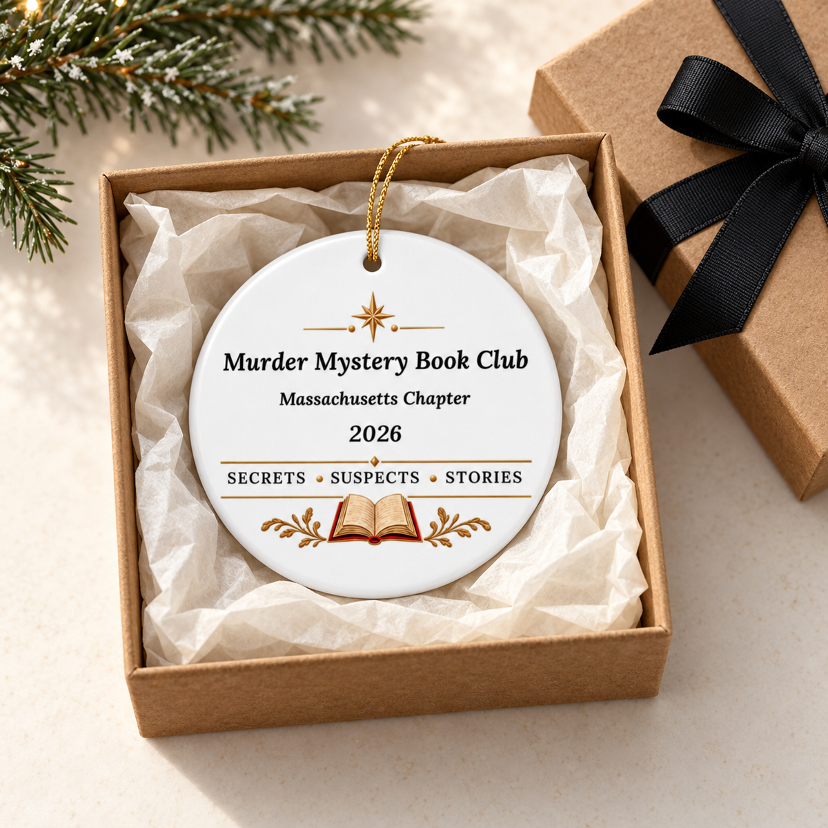 White round “Murder Mystery Book Club” ornament in a tissue-lined brown gift box, with Massachusetts Chapter, 2026, “Secrets • Suspects • Stories,” gold accents and an open book.