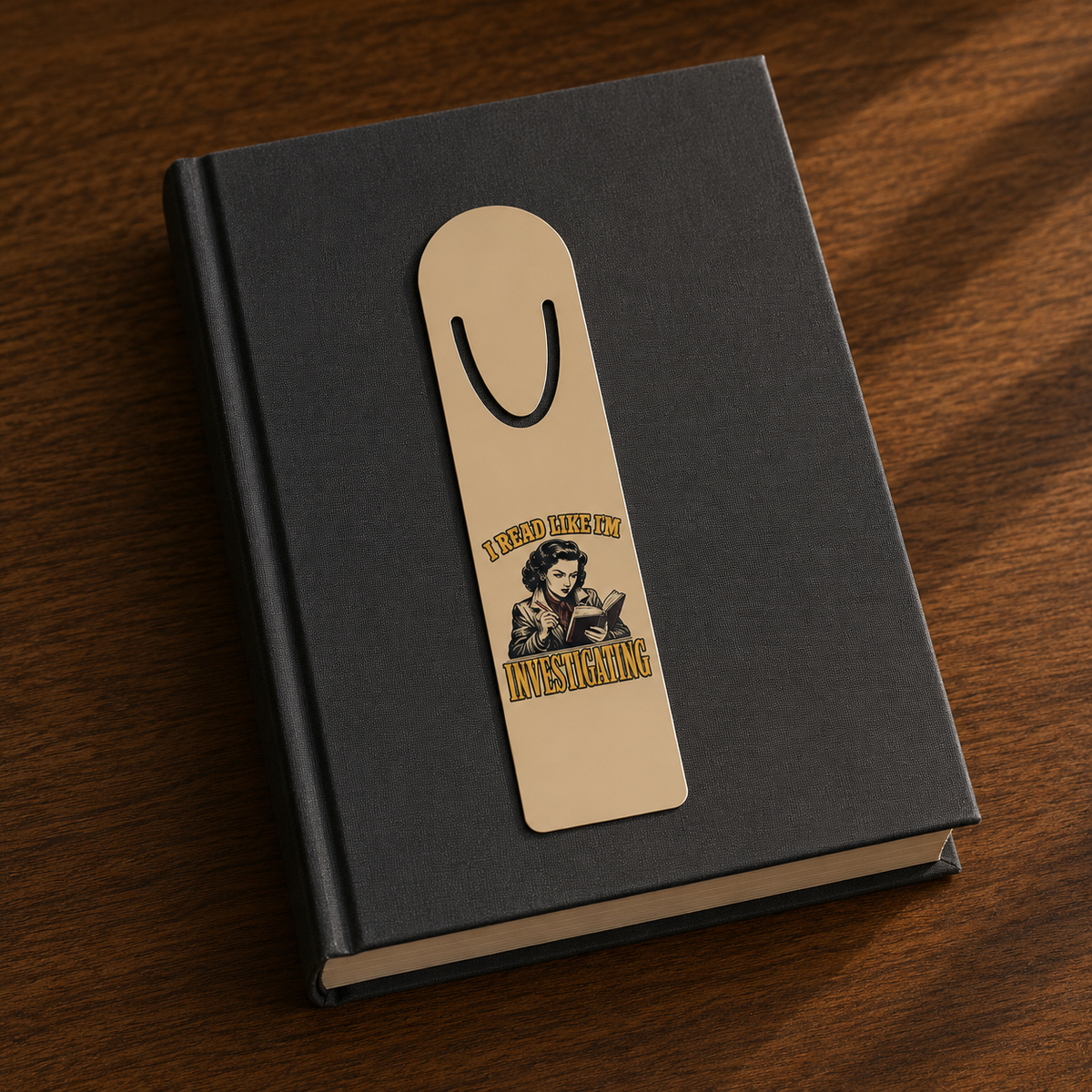 I Read Like I’m Investigating aluminum bookmark displayed on a closed black hardcover book.