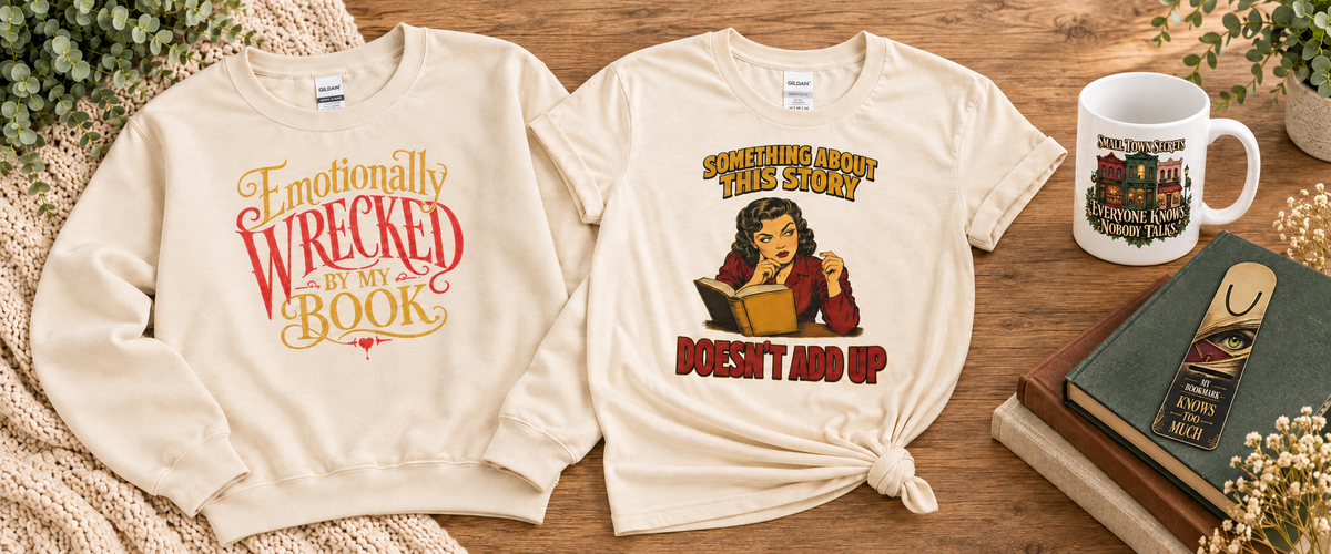 Book-themed sweatshirt and mystery-reader T-shirt beside a Small Town Secrets mug and My Bookmark Knows Too Much bookmark on stacked books.